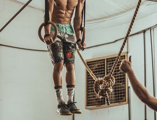 gambaru crossfit man wearing multicolored shorts while exercising on rope inside white room brazil